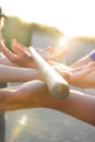 Blurred hands hold a blurred, wooden stick. teambuilding activity with a stick and hands. colleagues. rays of the sun fall, light