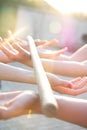 Blurred hands hold a blurred, wooden stick. teambuilding activity with a stick and hands. colleagues. rays of the sun fall, light