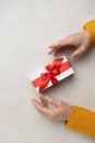 Blurred imag Woman holding a white gift box with a red bow in her hands