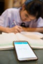 Blurred image of asian girl doing homework while being time by a