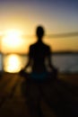 Blurred image back woman sitting in a lotus pose on the wooden p