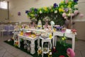 Blurred image of birthday party decoration with tables, balloons, candies and cake.