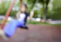 Blurred image of boy child swinging on swing chair park playground outdoors alone young toddler playing urban city playing site