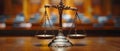 Blurred image of brass scales of justice and wooden judge gavel on a desk in a legal office.