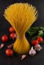 Blurred image of a bunch of spaghetti with tomatoes, garlic and herbs on a black background