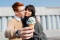 Blurred image of couple sitting outdoors with ice cream, kissing. Blurred faces