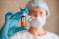 Blurred image: doctor holding syringe and coronavirus Covid-19 vaccine vial. Vaccination, pharmaceutical research concept