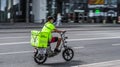 Blurred image of a food delivery courier delivering food on electric bicycle. Cyclist carrying backpack with food and drinks