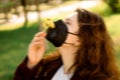 Blurred image. girl in a black mask with flowers on the street. Walk during quarantine, a girl picks flowers in the summer.