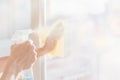 Blurred image of hands with napkin cleaning window. Woman hands washing the glass on the windows at home with spray.