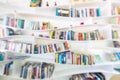 Blurred image of many books on curved bookshelf in library background. Royalty Free Stock Photo