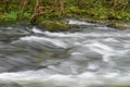 Blurred image of the movement of water in a beautiful forest river with a waterfall Royalty Free Stock Photo