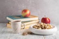 Blurred image of a plate of cookies, a cup of coffee and a book with apples on the background