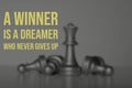 Blurred image of queen chess defeat pawn with text A WINNER IS A DREAMER WHO NEVER GIVES UP