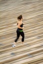 Blurred image of Woman jogging on rows of wood venue seating