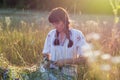 Blurred image of a woman who weaves a wreath of wild flowers in