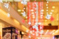 Blurred interior of shopping center or mall festively lit and decorated with shiny red white garlands. Background for holiday, Royalty Free Stock Photo