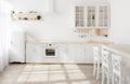 Blurred light sunny kitchen in Scandinavian style. White kitchen furniture and dining area, copy space Royalty Free Stock Photo