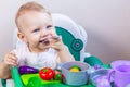 Blurred little child holding a toy vegetable in his hands on the background of dishes Royalty Free Stock Photo