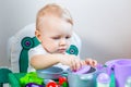 Blurred little child holding a toy vegetable in his hands on the background of dishes Royalty Free Stock Photo