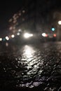 Blurred low angle view of car headlights shining in rain with reflection on wet cobbled at night Royalty Free Stock Photo