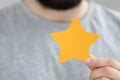 Blurred male holding a yellow paper star, Feedback, review and rating concepts Royalty Free Stock Photo