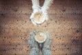 Blurred male`s and female`s hands in the knitted mittens with an cup of coffee under a glass roof with raindrops.