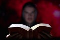 Blurred man on dark background holding a book in his hands