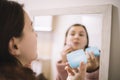 Blurred mirrored image of girl with face cream