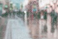 Blurred motion abstract background, raindrops on window glass, people walk on road in rainy day. Concept of shopping, modern city Royalty Free Stock Photo