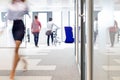 Blurred motion of businesswoman walking with male colleagues in background at office Royalty Free Stock Photo