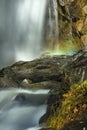 Blurred motion of a waterfall with a rainbow in mist. Royalty Free Stock Photo