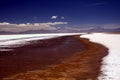 Blurred mountain range under dramatic cloud carpet contrasting with white and blue shimmering salt lake