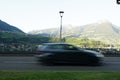 Blurred moving car on the road with rocky mountains in the background in Meran city