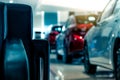 Blurred new luxury red and gray car parked in modern showroom. Selective focus on black leather sofa in modern showroom. Car Royalty Free Stock Photo