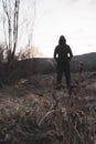 A blurred out of focus edit. A moody hooded figure, standing in the countryside looking at the evening sky. With a vertical