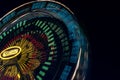 Blurred part of a Ferris wheel at night with changing colors. Ride spinning, creating light streaks at night