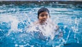 Blurred photo of a young asian happy kid swimming inside the swimming pool splashing water Royalty Free Stock Photo