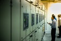 Blurred portrait of technician doing the preventive maintenance in the control room. Workers monitoring the status of electronic