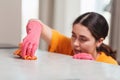 Blurred portrait of a young woman in rubber gloves is busily wiping the table with a rag. Close-up. House cleaning