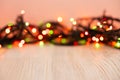 Blurred product background with Christmas New Year colorful light bulbs garland and wooden table. Selective focus, copy space for Royalty Free Stock Photo