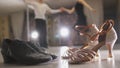 Blurred professional man and woman dancing Latin dance in costumes in studio, two pairs ballroom shoes in the foreground