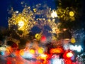 Blurred rain drops on car window with road light bokeh on rainy season abstract background