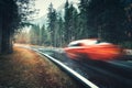 Blurred red car in motion on the road in autumn forest Royalty Free Stock Photo