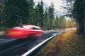 Blurred red car in motion on the road in autumn forest in rain Royalty Free Stock Photo