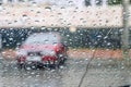 Blurred red car, the silhouette through the water droplets on the windshield with a focus on a few drops of water Royalty Free Stock Photo