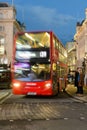 Blurred red London bus travelling through Piccadilly Circus at dusk