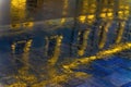 Blurred reflection of a bright building in a puddle on the asphalt. Rain in the city at night. Abstract vivid colorful