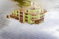 Blurred reflection of bright colorful building in puddle. Rain in city. Abstract scenic background