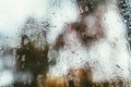 Blurred reflection of the street in a misted window, drops of water after rain flow down the glass. Water drops on window. Rainy Royalty Free Stock Photo